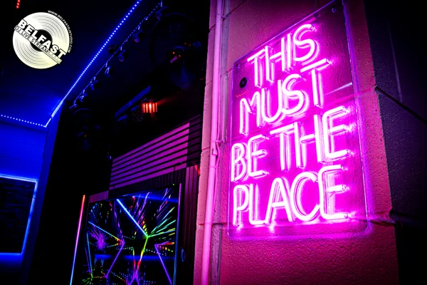 Pink neon sign reading This must be the place